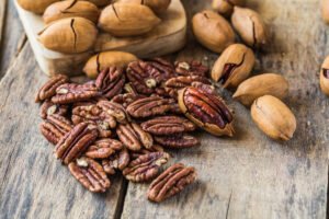 Nueces pecanas peladas y con cáscara sobre una mesa de madera.
