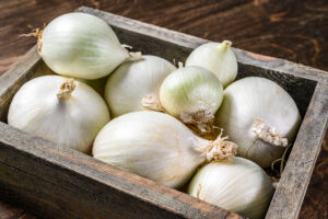 White raw onion in wooden box. Wooden background. Top view