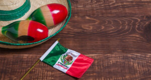 Maracas, Mexican flag and Mexican hat on wooden table. Mexican background.